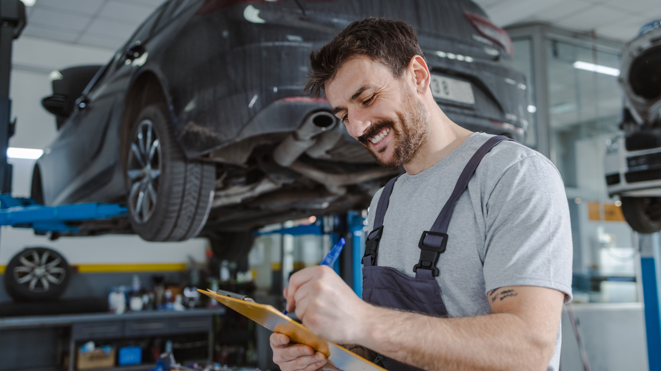 Werkstattmitarbeiter in einer Autowerkstatt, der einen Auftrag ausfüllt.